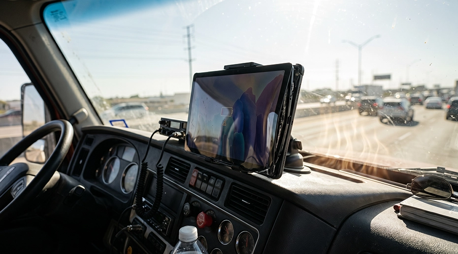 Consumer tablet battery swelling and screen warping on a hot commercial truck dashboard under direct sunlight.